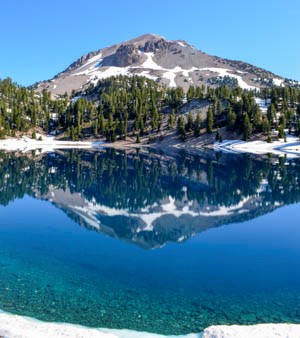 A volcanic peak reflected in a bright blue lake.