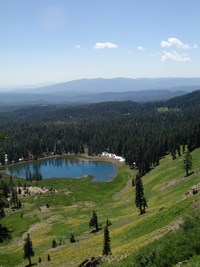 view of meadow surround Crumbaugh Lake with mountains and sky with clouds in background