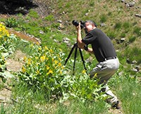 A man looking through a camera on a tripod