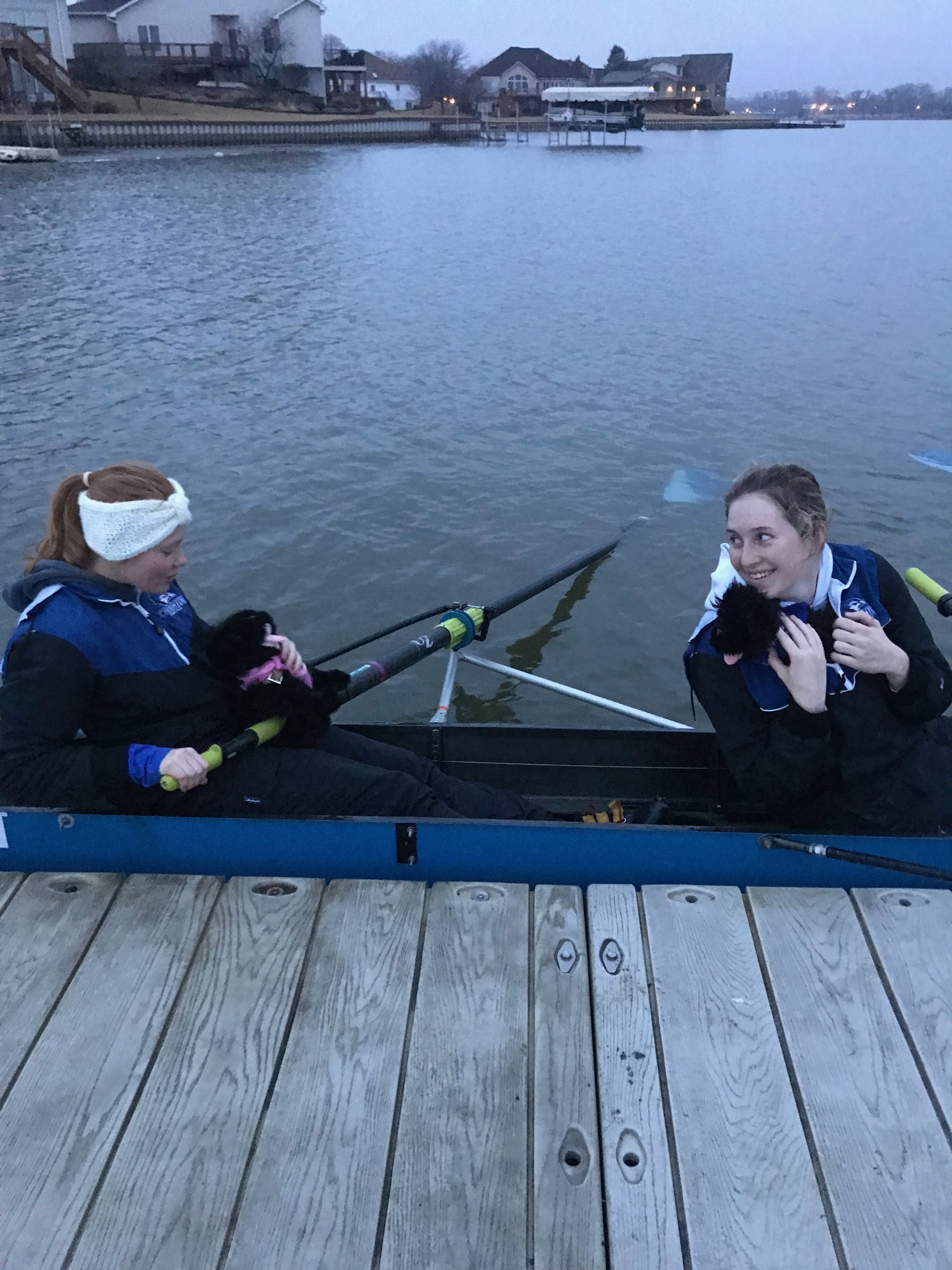 Two women holding pups in a boat