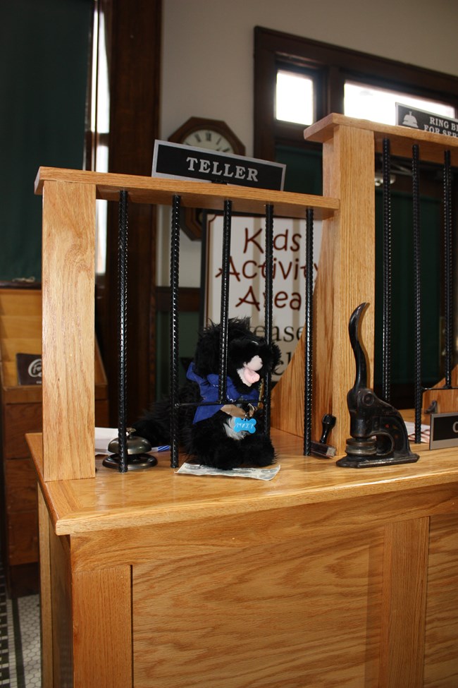 Stuffed pup behind bars of a historic bank desk