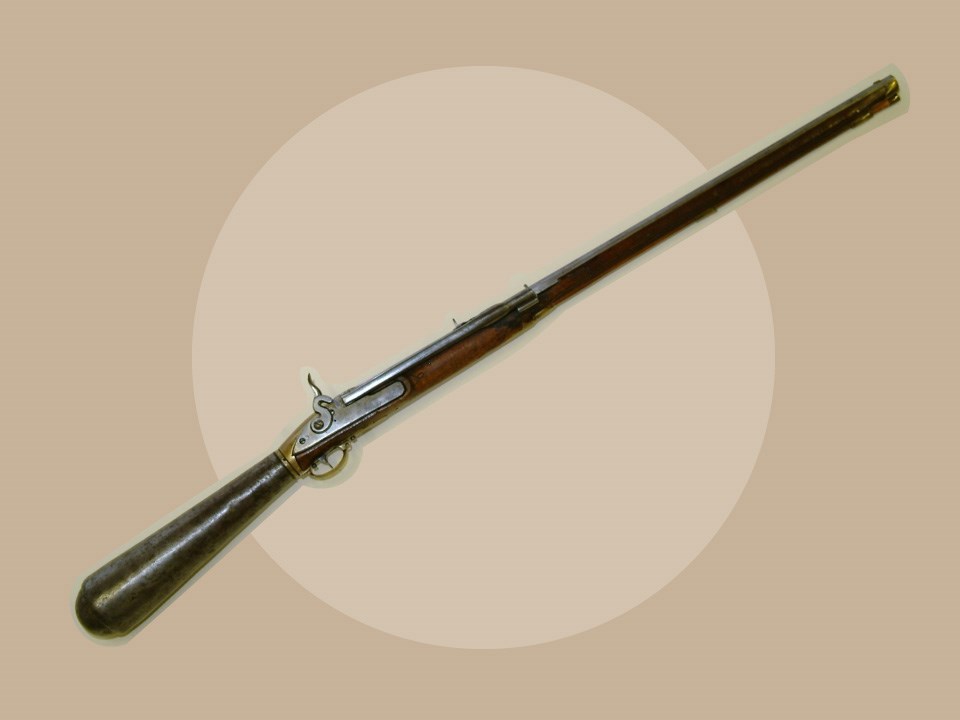 Air-Rifle Photo of early 1800s rifle with wooden handle and barrel. Tan background.
