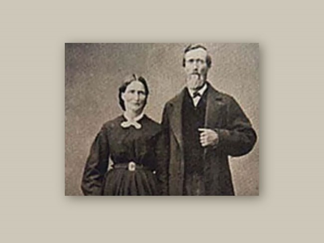 A black-and-white photograph showing Alexander and Eleanor standing side-by-side wearing dark-colored, mid-19th century period clothing.  He has a neatly trimmed beard; both have solemn facial expressions.