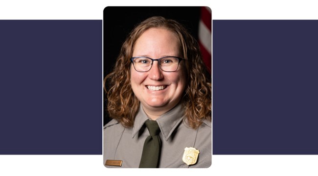 Portrait of woman wearing park service uniform. shoulder length curly reddish hair. American Flag in background.