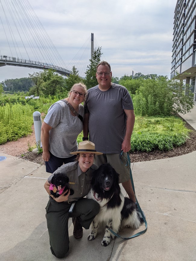Ranger poses with Newfoundland dog and two visitors.