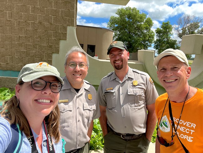 Four people pose for a selfie. Two men in center wear NPS uniforms Woman on the left, man in far right.