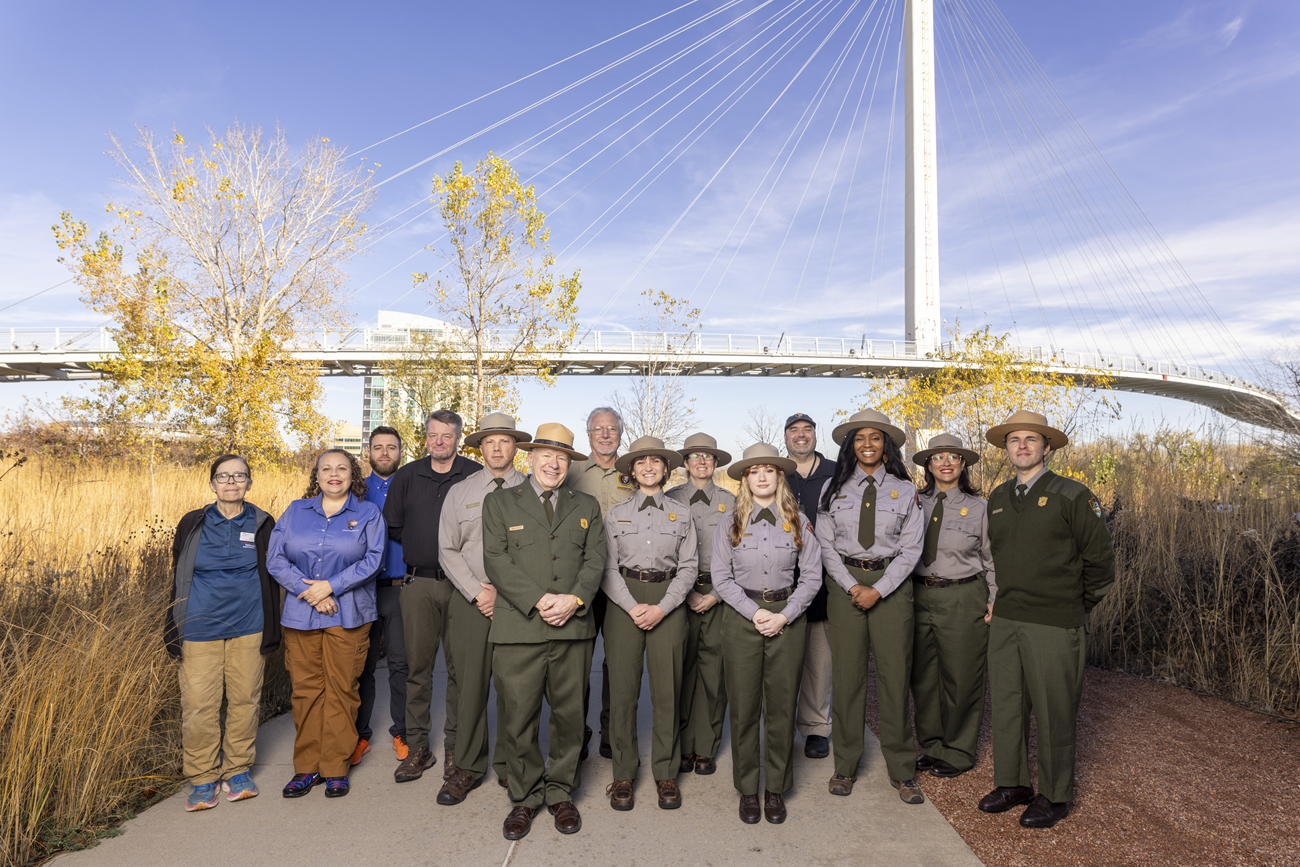 a group of people in ranger uniforms and business wear in front of a walking bridge
