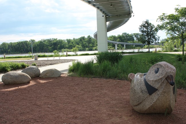 Path next to a river. Large sculpture of shorebird.