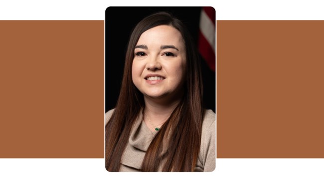 Portrait of woman with long brown hair. American flag in background.