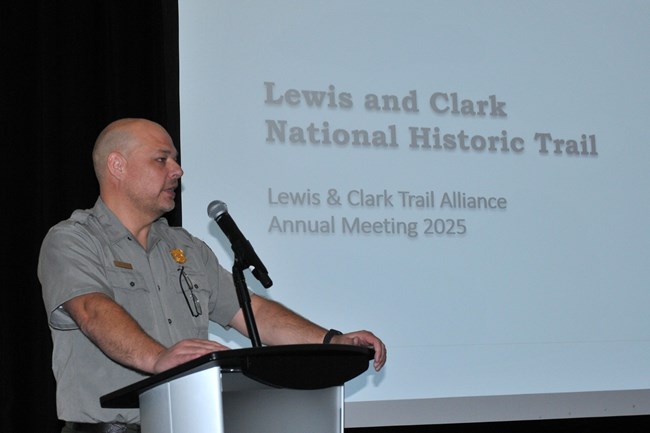 a man in a park ranger uniform speaks into a microphone