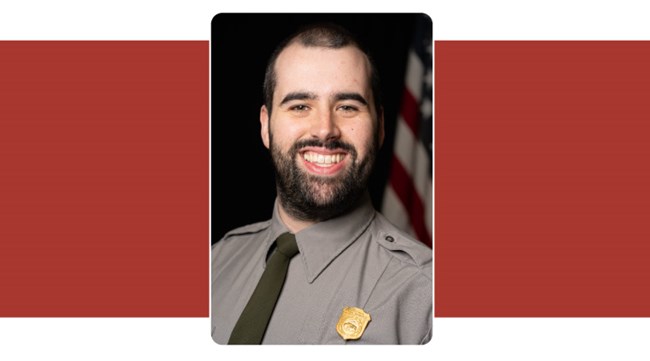 Portrait of man in uniform with short brown hair smiling broadly. Park Service Uniform. American Flag background.