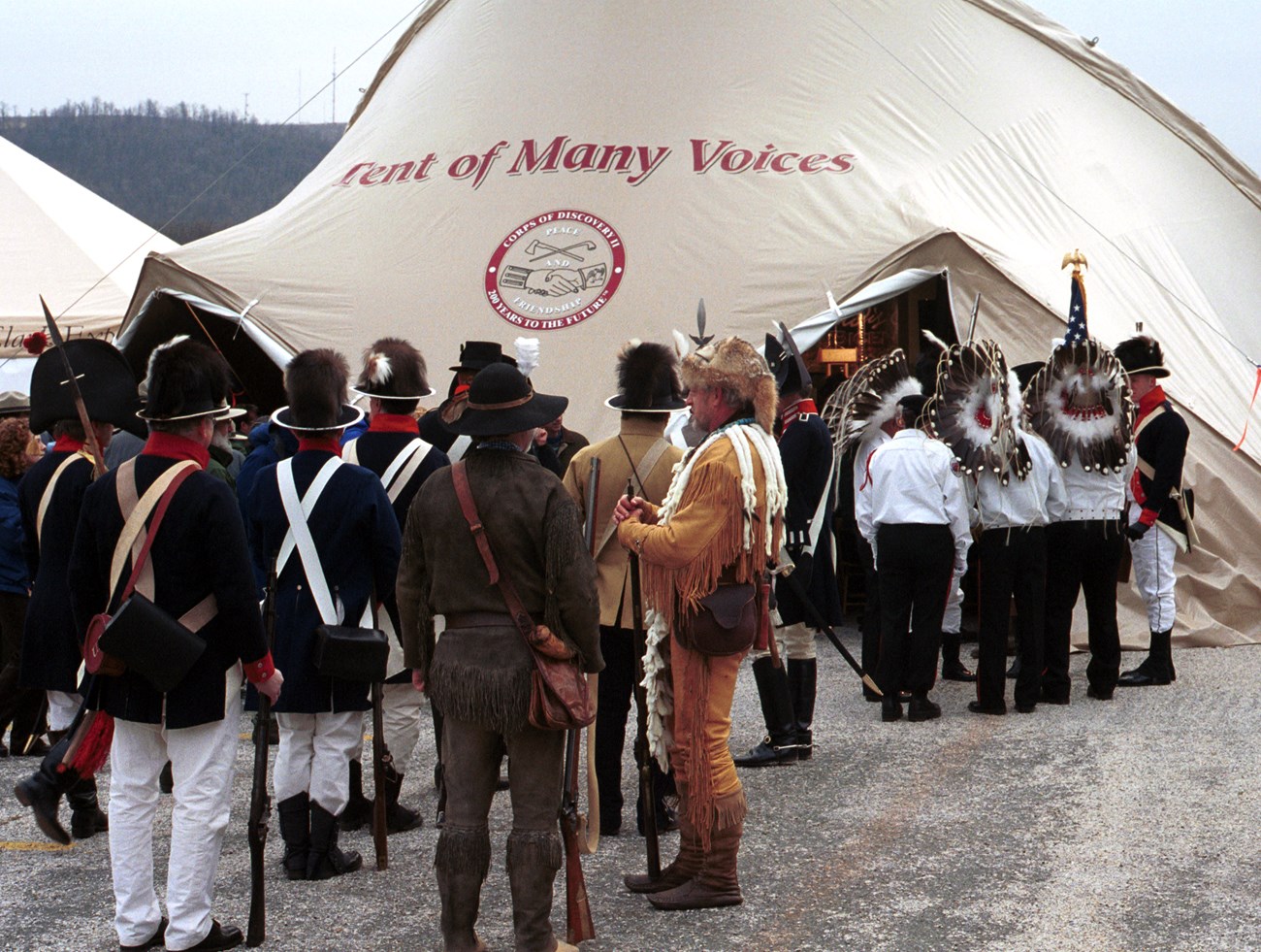 many people in 1800s clothing standing outside of a tent
