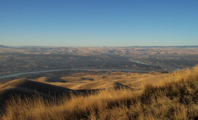 Dry grasses on the hills above the Snake River. A town is faintly visible along the river.