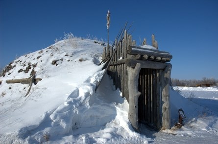 Earth lodge nearly covered in snow