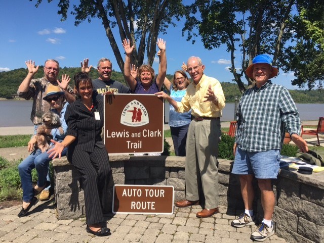 Auto Tour Route signs_Augusta KY _2021-09-09 Eight people smile and wave, grouped around Lewis and Clark Trail Auto Tour Route Sign.