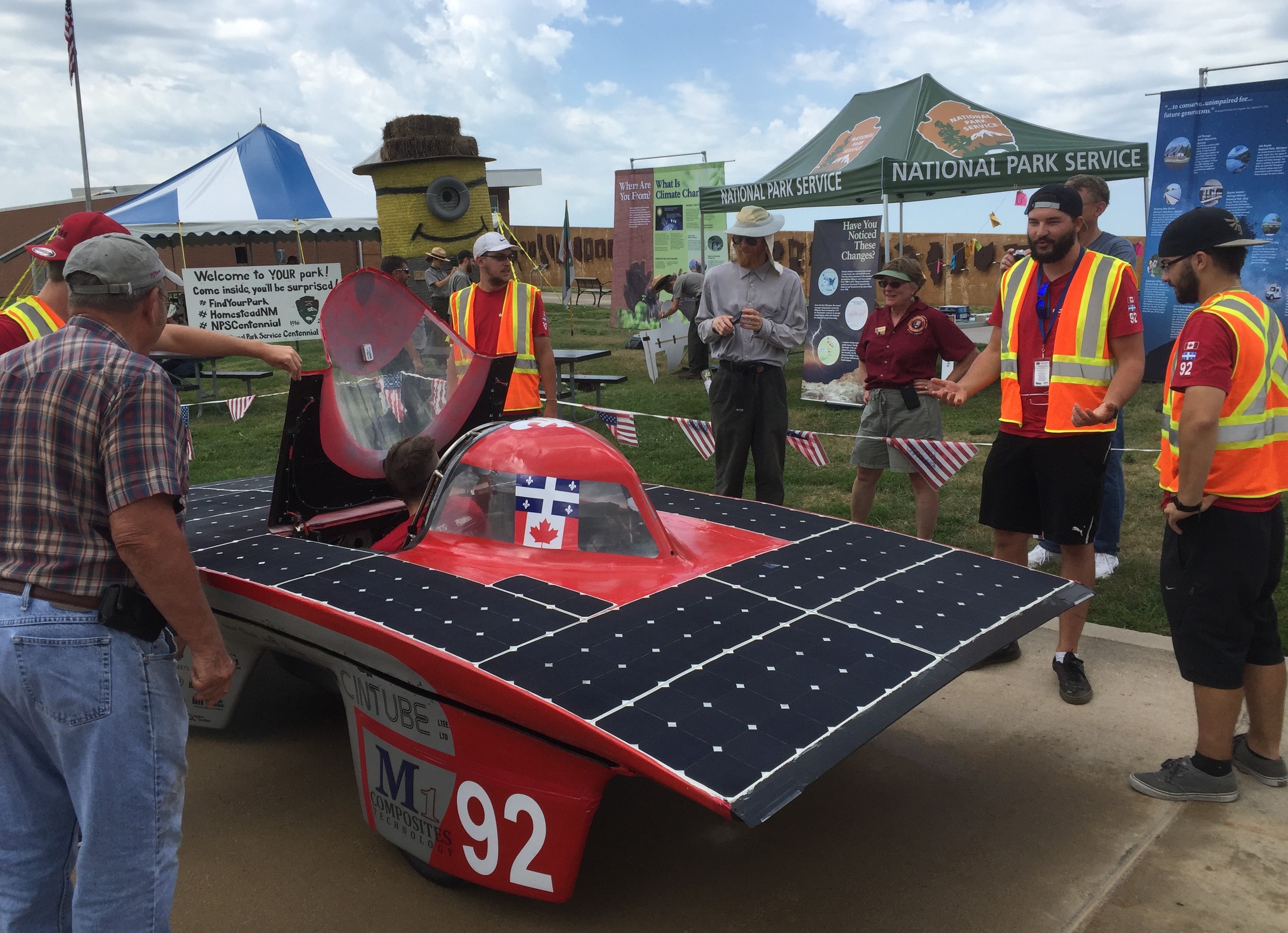 Multiple people standing near a solar car.