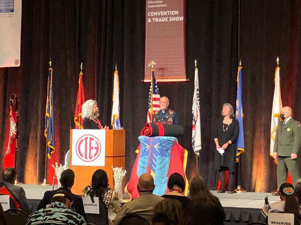 Group of four people on stage. Podium reads NIEA. On