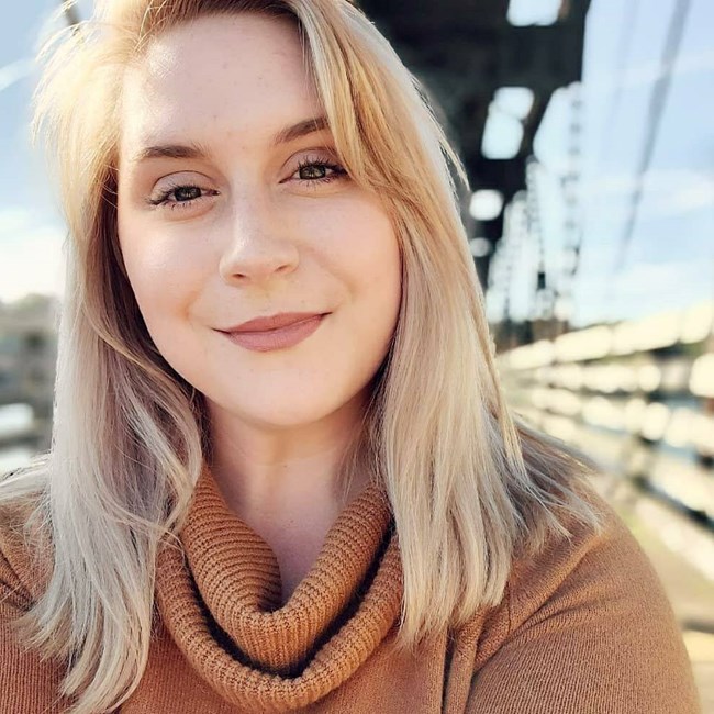 Young person with shoulder length blonde hair smiles