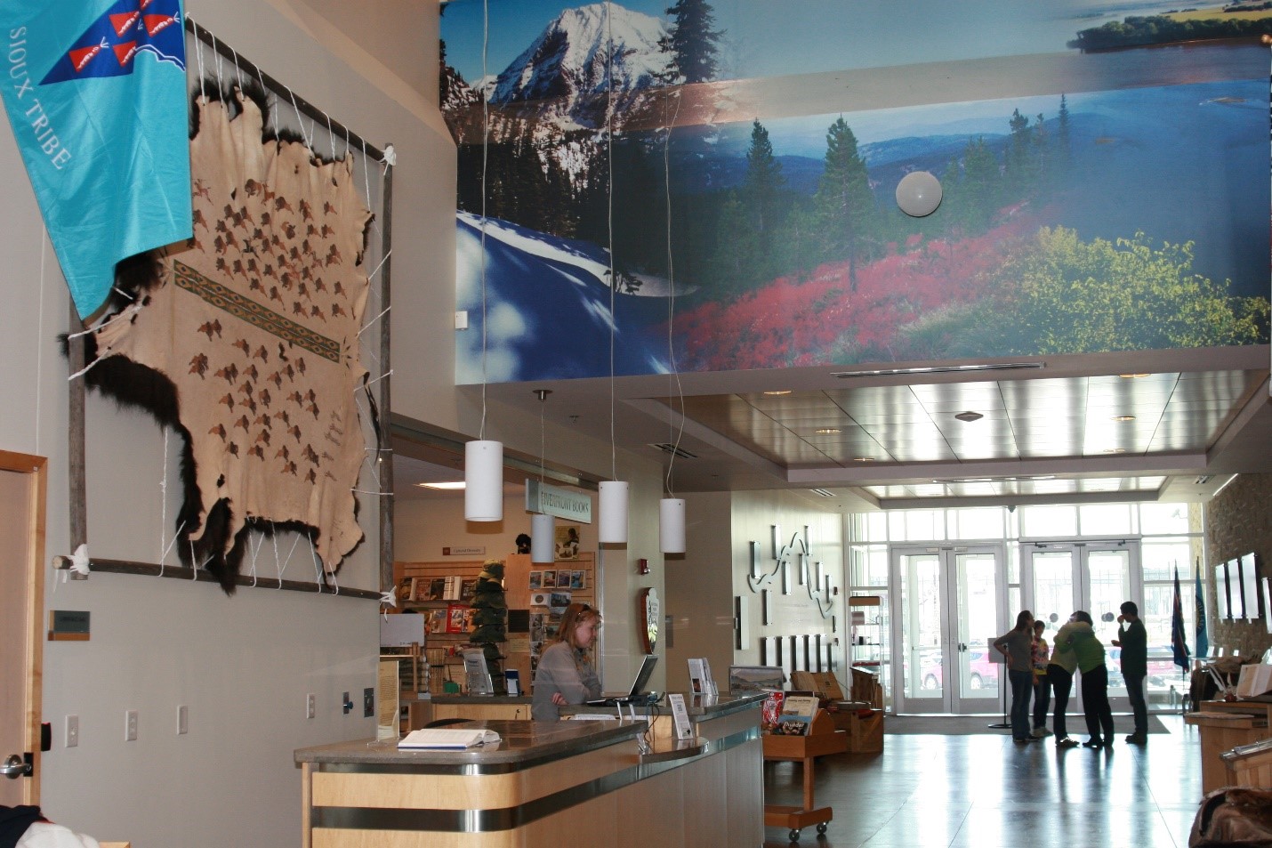 A ranger works at a computer while Lewis and Clark National Historic Trail visitors mingle in the background.