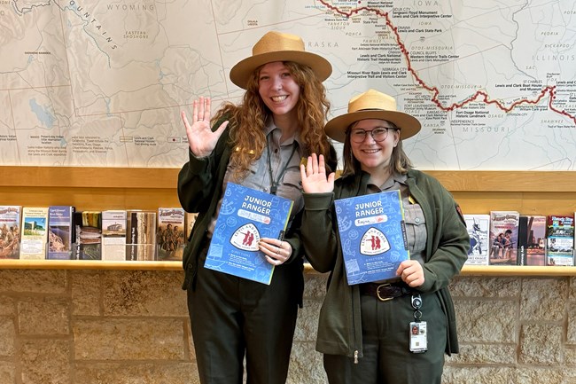 Two park rangers holding Junior Ranger booklets