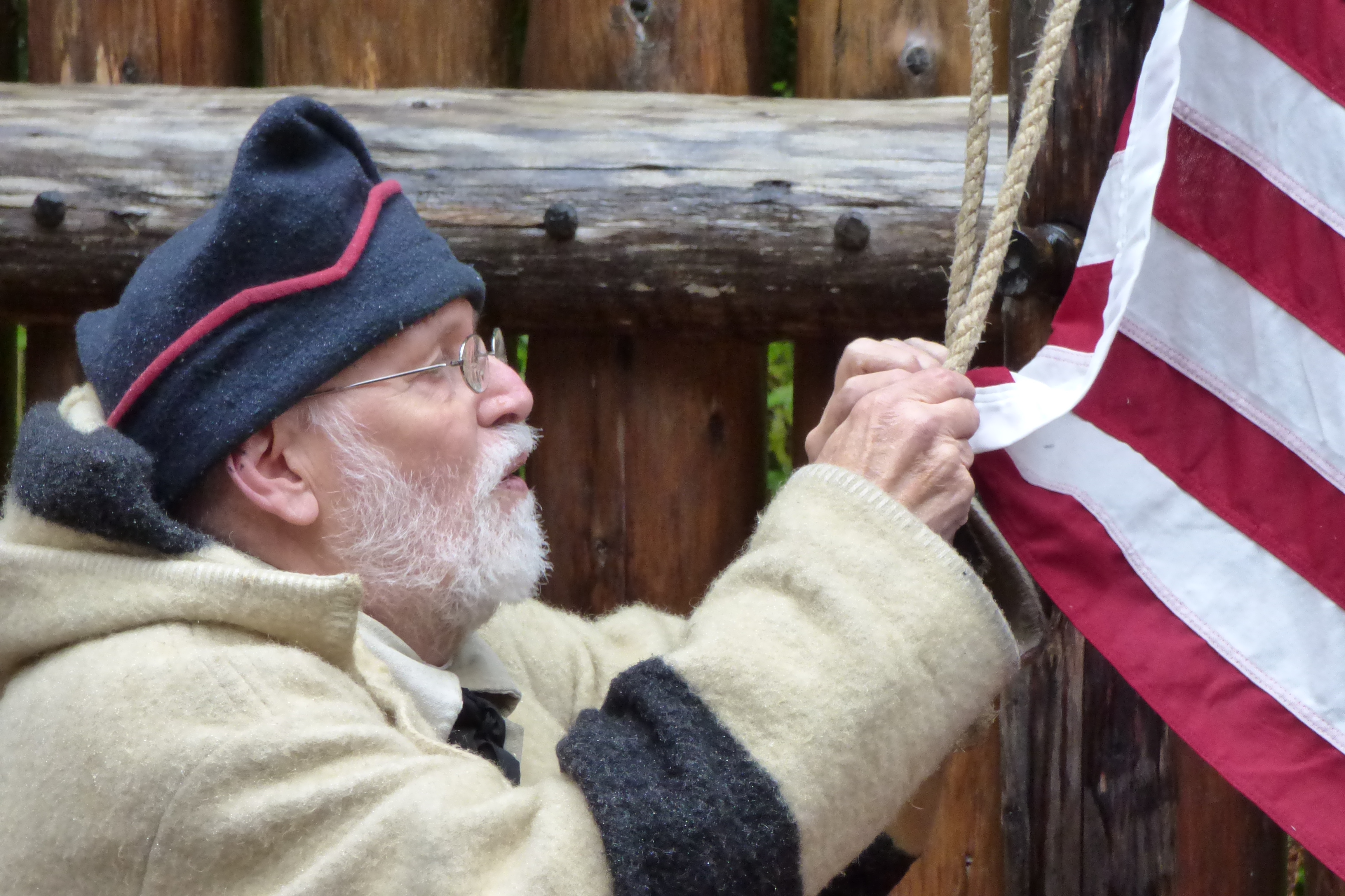 Bill in costume tying flag A male park ranger in historical costume ties an American Flag to a rope