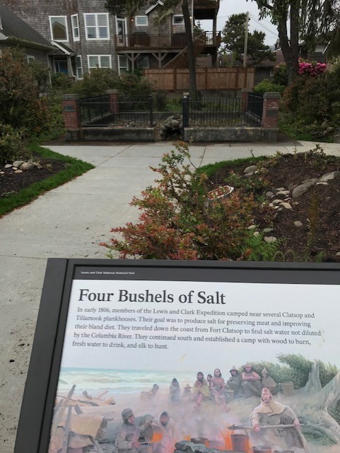 The Salt Works in Seaside An interpretive sign on salt stands infront of the reconstructed Salt Works protected behind iron bars