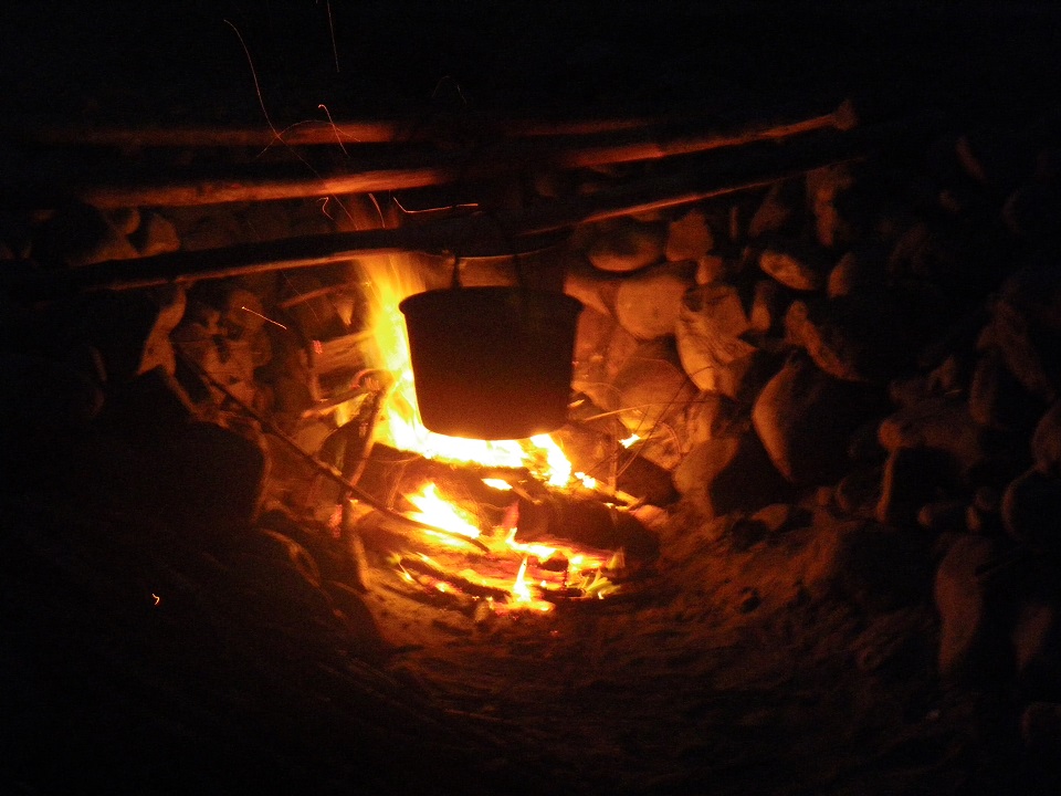 A pot boils water above a fire in a salt cairn
