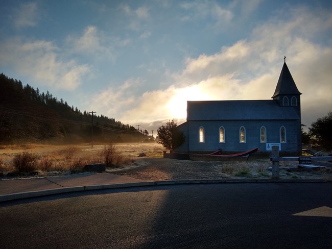 Concrete canoes in the foreground with a church in the background amid a field at Middle Village