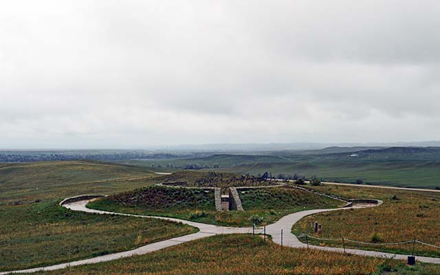 The Indian Memorial is wet after a rainstorm has occurred. The sky is cloudy, and the grass surrounding the memorial is a darker green. The Indian Memorial is wet after a rainstorm has occurred. The sky is cloudy, and the grass surrounding the memorial is a darker green.