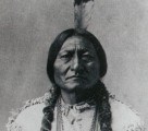 Black and white photograph of Sitting Bull with a single feather in his hair.