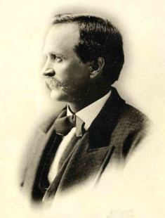 Side portrait of Charlie Reynolds wearing a bow-tie and a jacket.