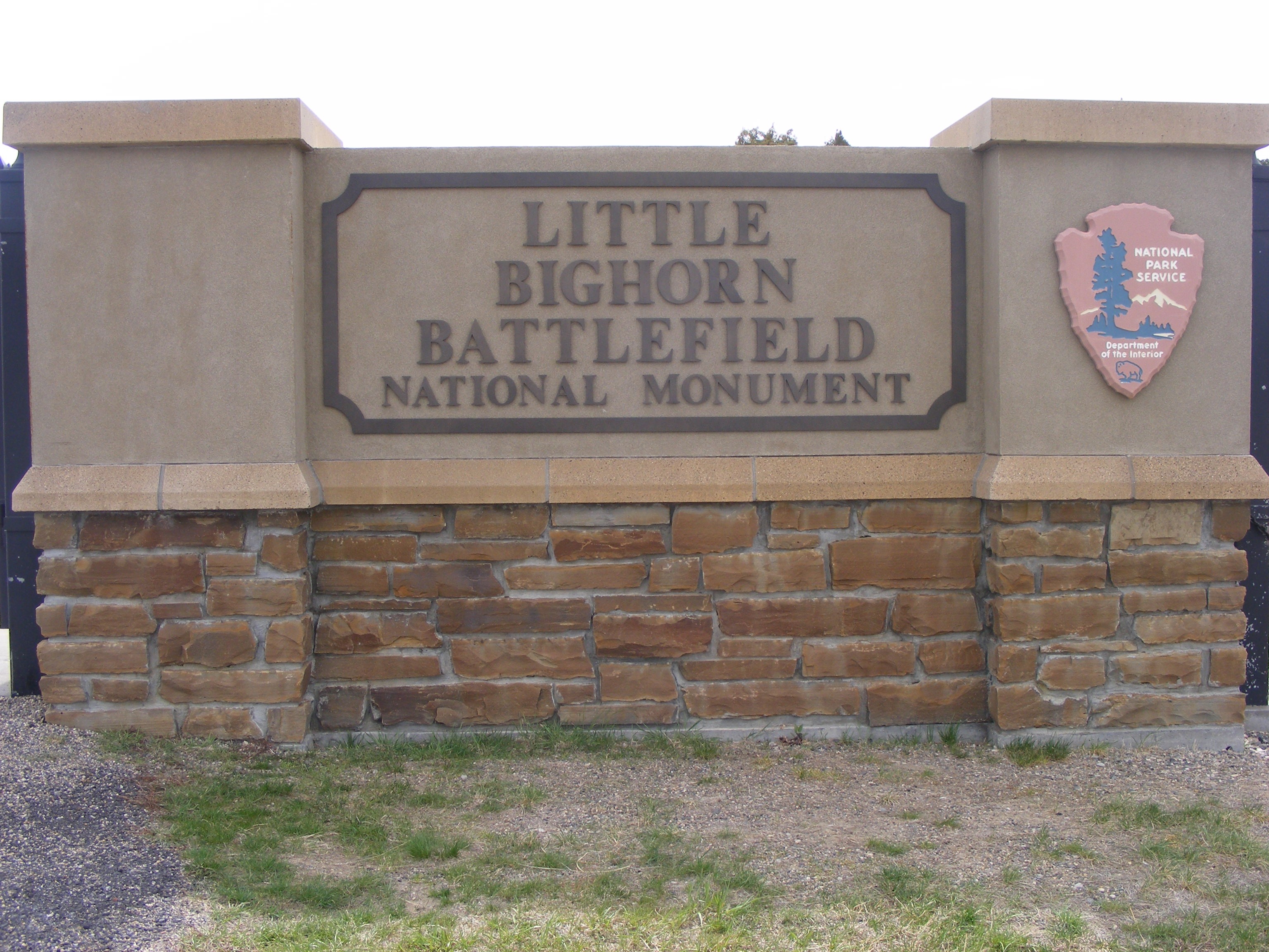 Little Bighorn Battlefield Entrance Station stone sign with National Park Service emblem to the right.