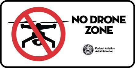 Black drone shape with red circle and slash. Words: No drone zone. Federal Aviation Administration