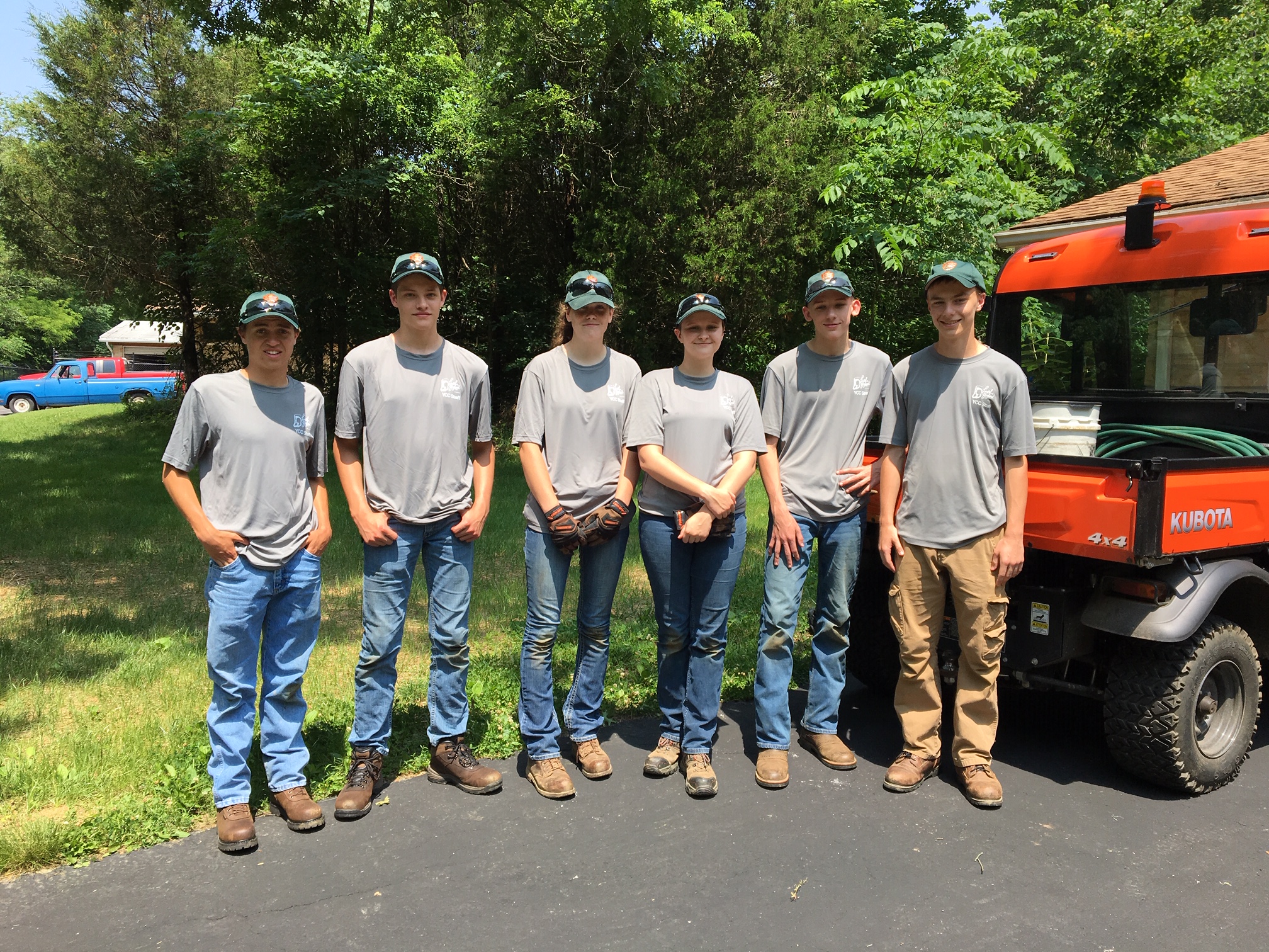 YCC Workers standing next to orange vehicle on park trail.
