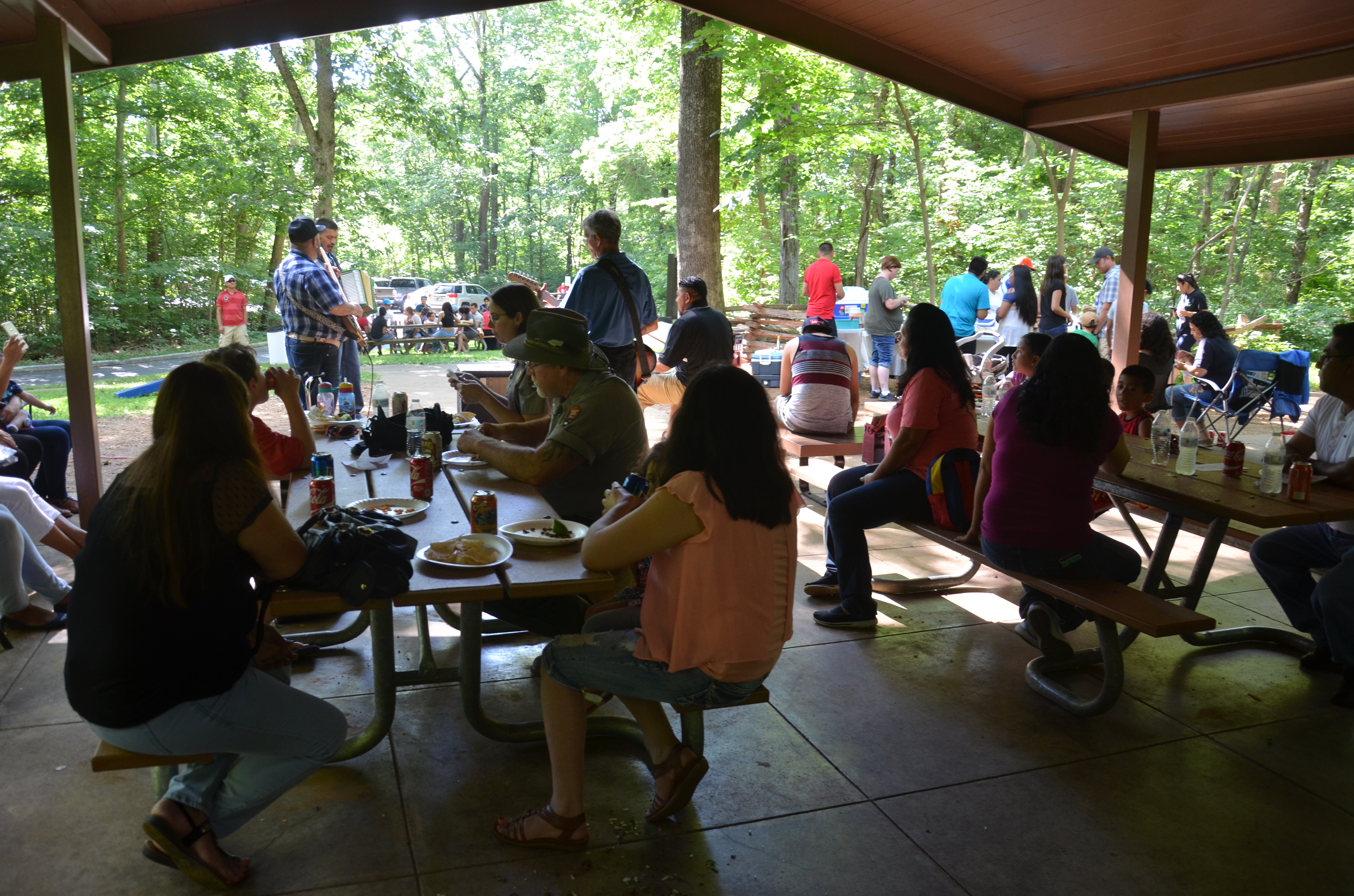 People enjoying food and music in park shelter during fiesta