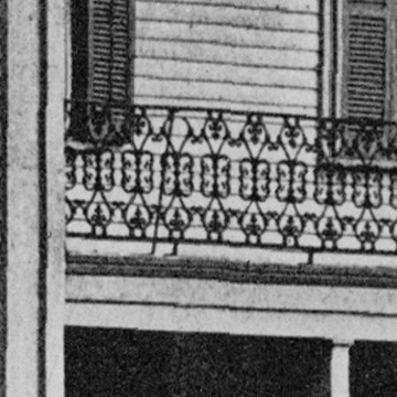 Close up photo of decorative, dark colored metal railing on Lincoln Home porch roof. A small piece of the railing seems to be missing.