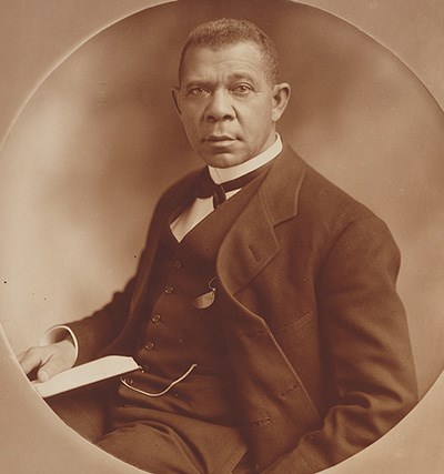 Distinguished-looking African American man with short cropped hair and sticking-out ears in a suit holding a paper or letter