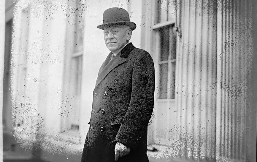 older man in round spectacles and dark bowler hat with faint white mustache