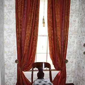 Dark red, sill-to-floor damask curtains with orange pattern