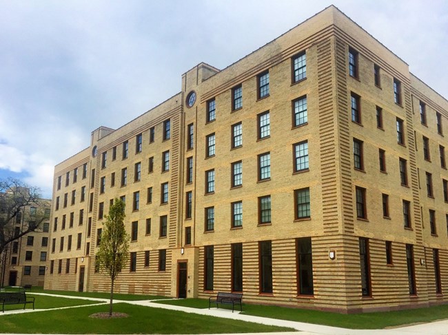 5-story yellow brick building wtih taller ground floor with tall, thin windows and regular 12-paned windows on all other floors