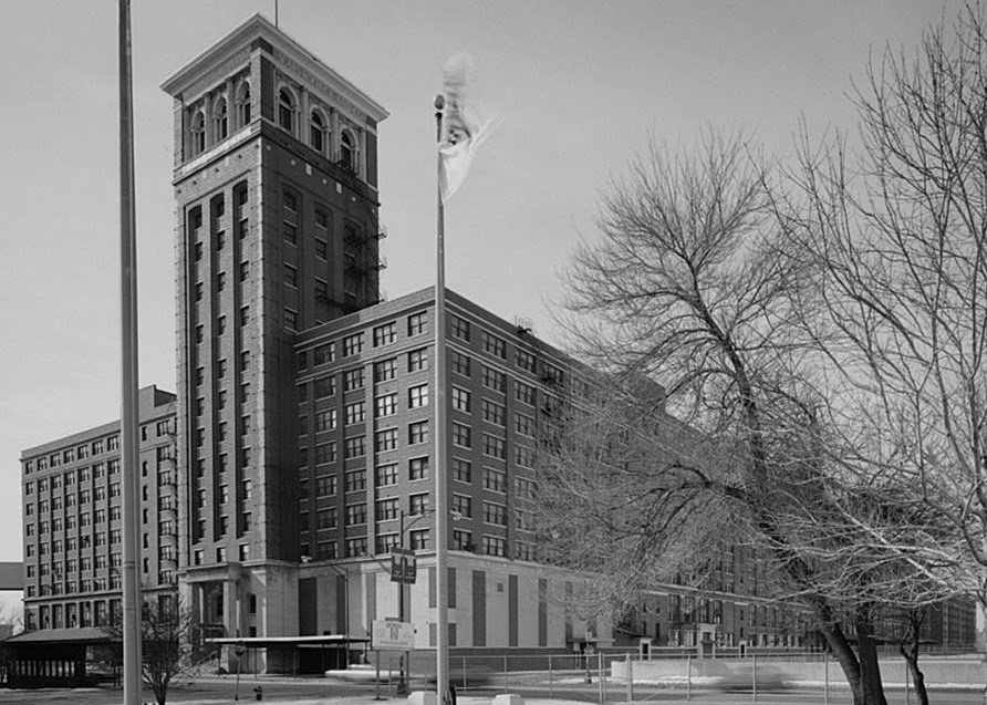 Large, multi-level brick building with taller tower section in front of building.