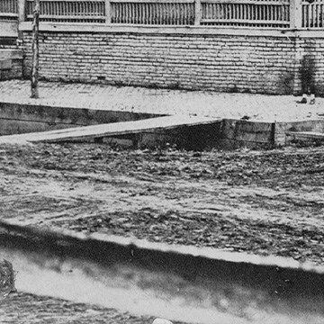 Close up of muddy streets at corner of Lincoln Home. Curbs are very deep and made of wood planks. Long wooden boards are laid against ground and curb as ramps.
