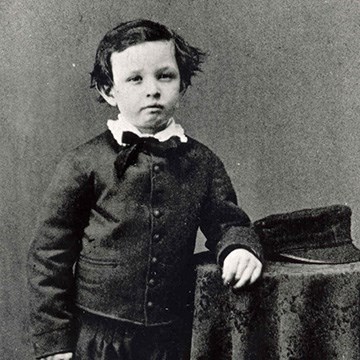 Young boy with mussed up hair leaning against table