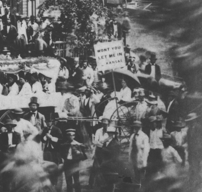 Cropped photo of 1860 Rally photo of woman holding sign with text: "Won't you let me in--Kansas"
