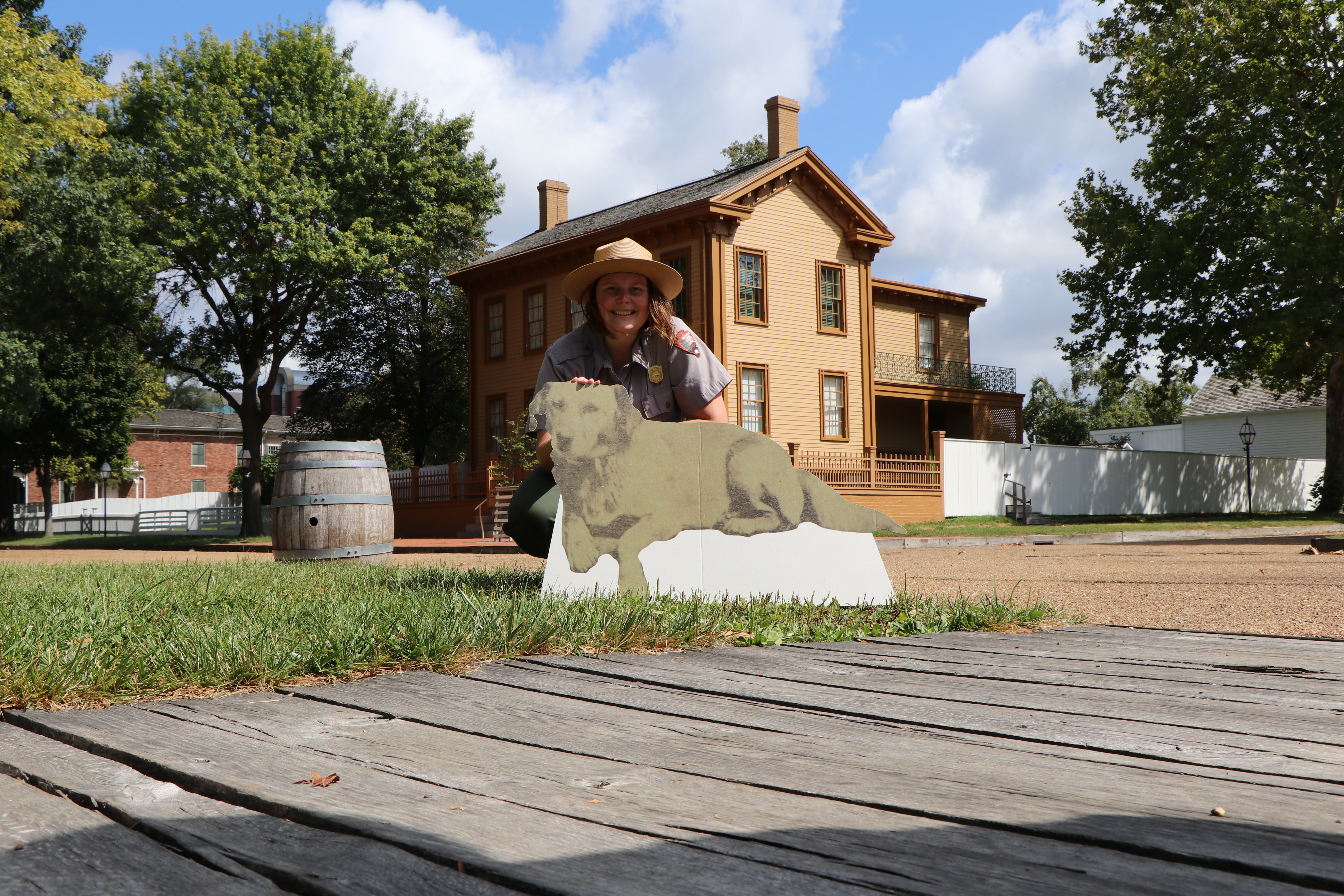 A park ranger poses with a cardboard cutout of a dog in front of the Lincoln Home