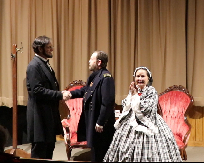 the cast of Message at Midnight: Randy Duncan, Dennis Rendleman and Pam Brown A photo depicting the three cast members of the play in costume during a performance. Randy Duncan as Lincoln shakes hands with Dennis Rendleman as Ulysses S. Grant while Pam Brown as Mary Lincoln looks out happily toward the audience.