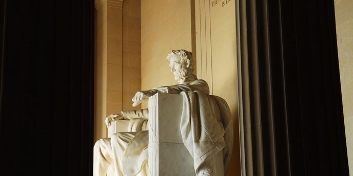 White statue of man resting his arms on chair looking off in the distance