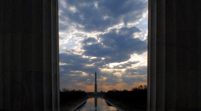 sunrise with washington monument in background, two columns in foreground on either side