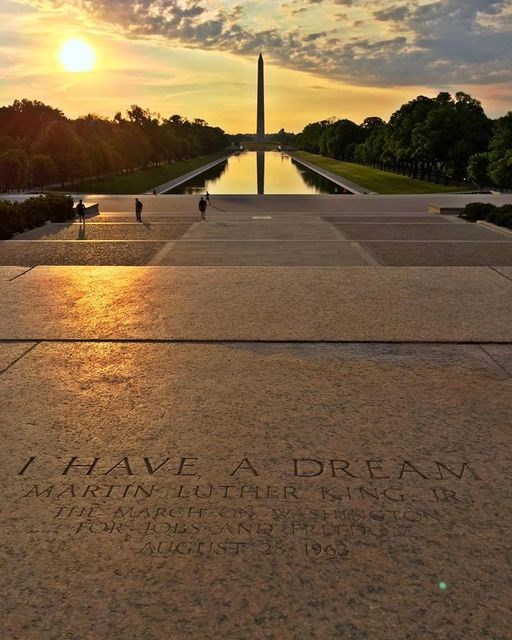 The sun rises over the Reflecting Pool, illuminating a stone that says "I have a dream."