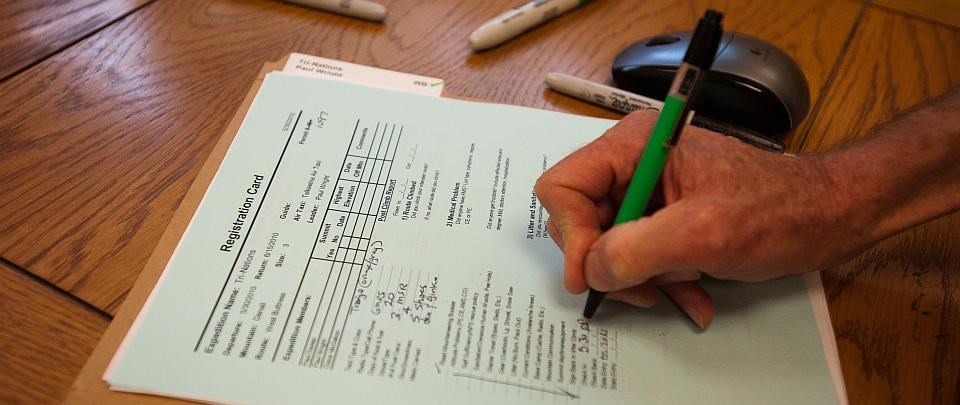 close up of a hand filling out a registration form